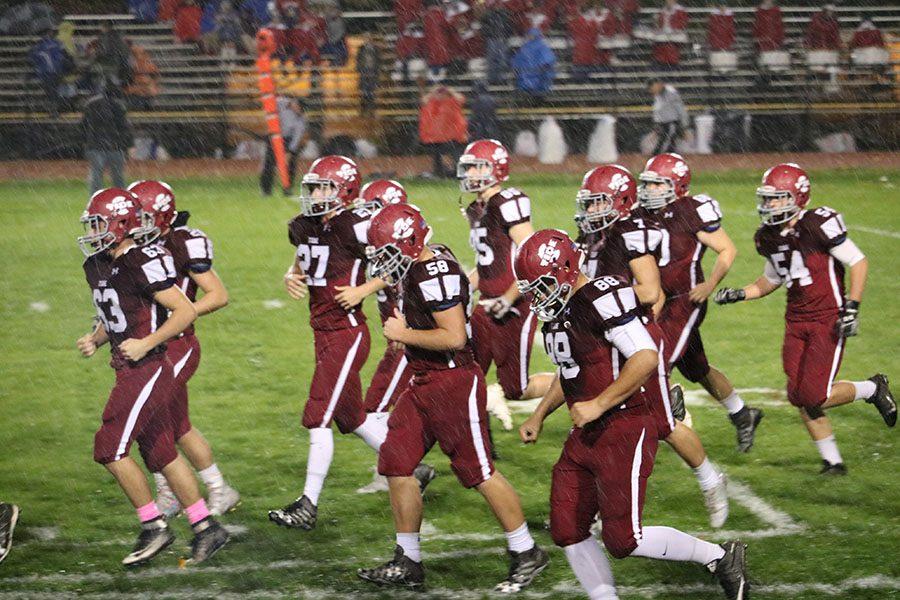 Teammates run through the rain during pregame. The score was tied around the first quarter but the Tide, eventually rose ahead for the win. “The rain didn’t affect how we played. We play 100% all the time,” junior, Solomon Serano football player said.

