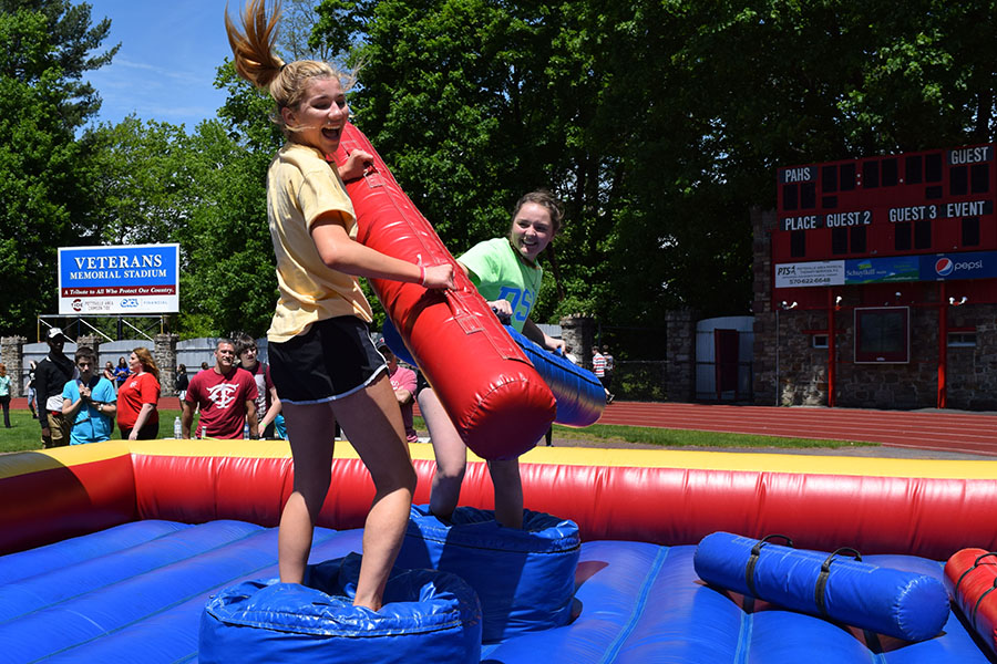 HIT — Juniors Hannah Sponenburg and Olivia Eagan battle it out during a jousting tournament. The lines for this blow up game and the blow up obstacle course were consistently long, but the warm weather kept everyone happy even when waiting for their turns. “I didn’t think the carnival was going to be as exciting as it was. It was way bigger and more intense than I expected and so much fun,” Sponenburg said.