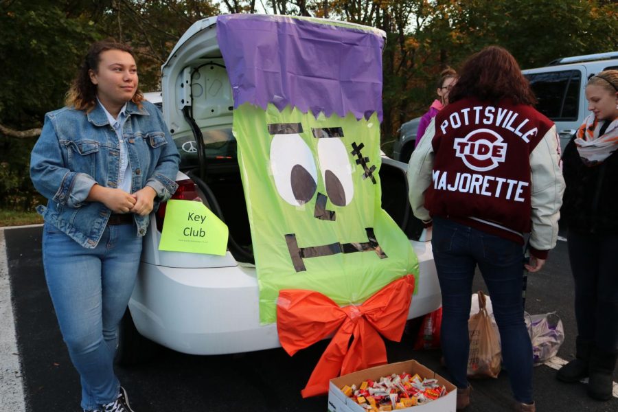 DECORATE - Junior Maya Jenkins and senior Gillian Revenis hand out candy by Key Club’s decorated car. “My favorite part of Trunk or Treat was seeing all the fun costumes and helping the kids have a good Halloween,” Jenkins said. Over 500 children came dressed up to celebrate Halloween safely with their parents and guardians in the middle school parking lot. 