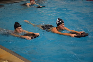 Sophomore Jadyn Wagner, left, and junior Lizzie Donovan, right, both hold a kickboard
 during practice. Wagner just began swimming. “Jadyn has improved greatly with her swimming abilities since she just joined the team,” coach Mr. Greg Schuettler said. 