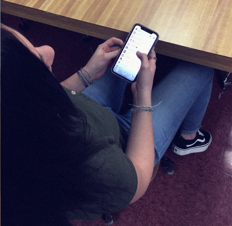 A+student+pulls+out+her+phone+in+class+during+school+to+check+her+Snapchat+for+updates.+Students+all+across+the+world+have+been+using+this+eight-year-old+app+that+has+made+a+name+for+itself+as+one+of+the+most+popular+social+media+platforms+to+ever+come+out.+%E2%80%9CI+would+say+that+our+generation+is+addicted+to+Snapchat.+It+has+become+a+regular+part+of+the+common+teen%E2%80%99s+day.+Not+only+to+message+people%2C+but+to+do+streaks+and+add+to+their+stories%2C%E2%80%9D+senior+Preston+Hunter+said.