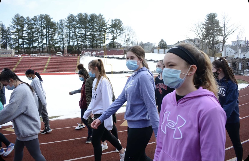 Junior Kaylee Becker and Emilee Rose are seen warming up their ankles at track practice.  Due to COVID there are restrictions at practice to wear a mask and social distance as much as possible. Junior Emilee Rose said, “ The first practice was definitely different from previous years, but I’m thrilled to be back to practice.”
