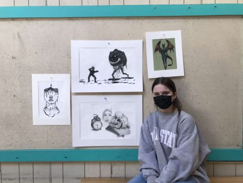 Artist Grace sits in front of her work. Her favorite piece is to the far left!